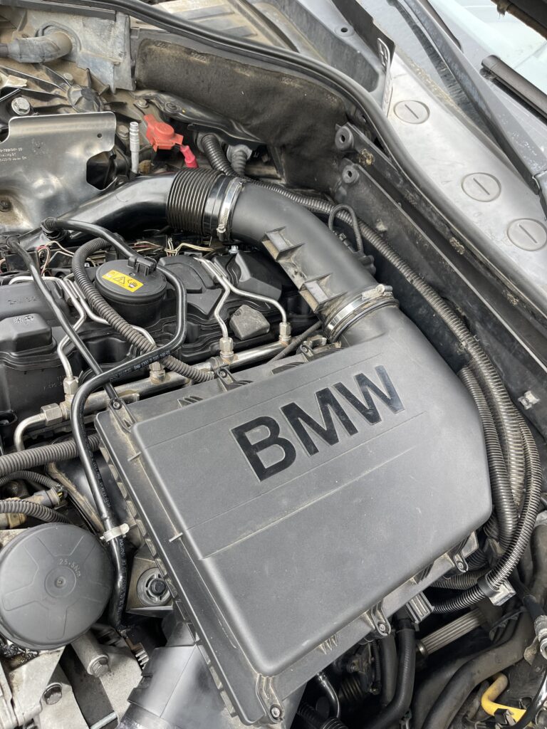 A close-up view of a BMW engine compartment, highlighting the air intake with the BMW logo.